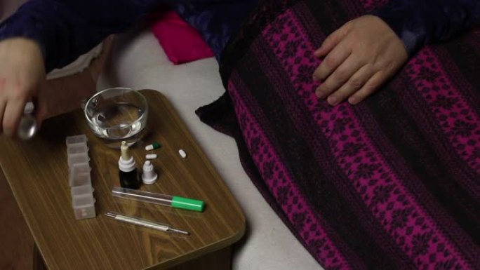 病人躺在铺着毯子的床上。给喉咙喷一剂。椅子旁边是各种药物。