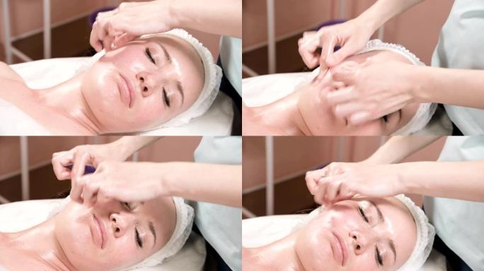 特写水疗面部按摩。女孩专业按摩治疗师为水疗沙龙的有吸引力的客户做放松的面部按摩