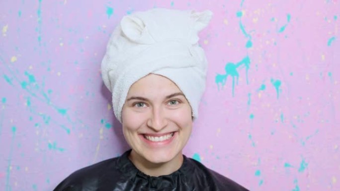 美容院的一名年轻女子在头上打着毛巾摆姿势。