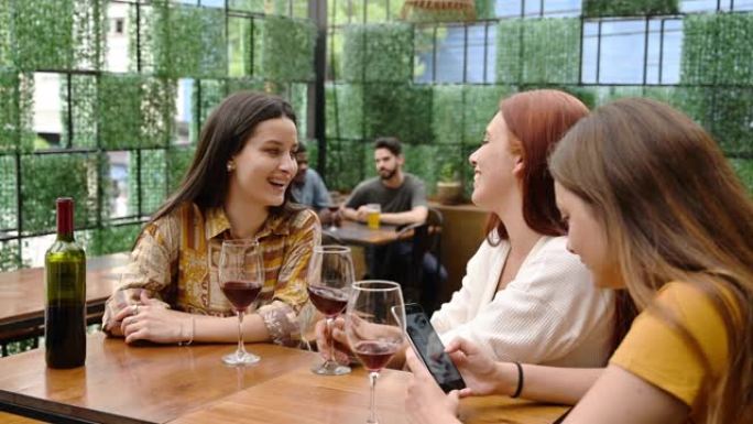 年轻的西班牙裔妇女在露天咖啡馆喝红酒放松