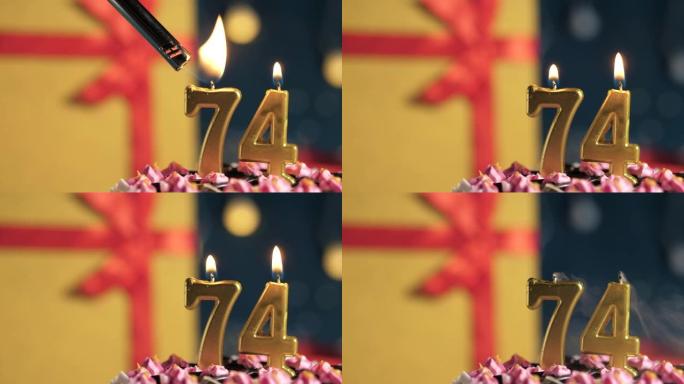 生日蛋糕74号点火器燃烧的金色蜡烛，蓝色背景礼物黄色盒子用红丝带绑起来。特写和慢动作
