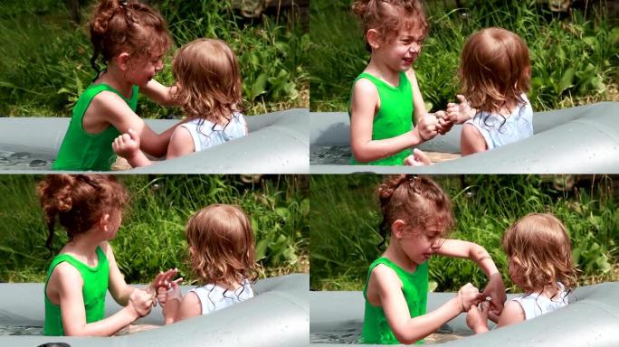 两个小女孩在后院的e充气游泳池内争夺橡皮筋
