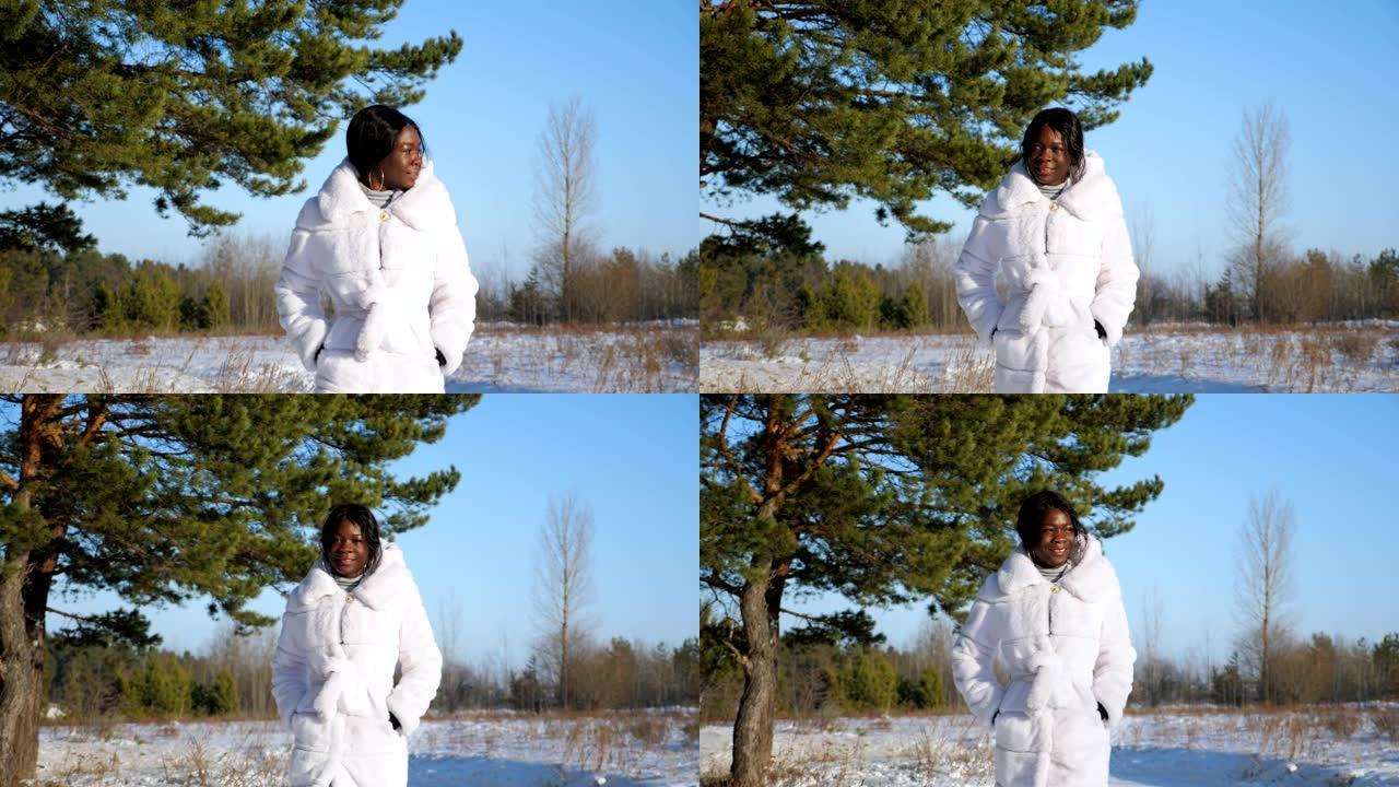 穿着皮大衣的黑皮肤女人在白雪皑皑的森林林间空地上行走