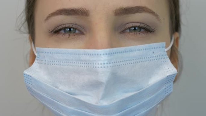 戴着保护性医用蓝色面具的女人的脸，特写。年轻女性戴着医用口罩预防和保护病毒感染。大流行保护新型冠状病
