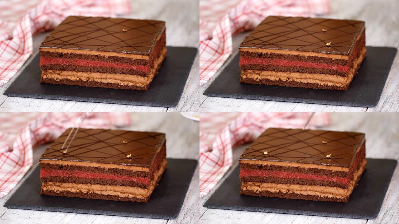 糕点师傅的手的特写镜头用金箔装饰巧克力蛋糕。
