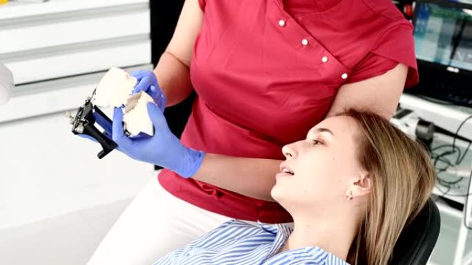 女牙医向年轻女性患者展示并解释石膏模型问题