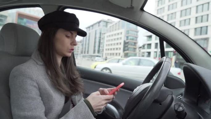 戴着黑帽子的年轻女子使用智能手机坐在驾驶员座位上