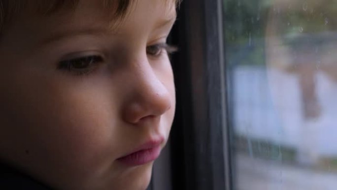 孩子透过窗户看。一个孩子在火车上向窗外看的特写镜头。特写后侧视图。坐火车旅行。这个男孩看着跑步的风景