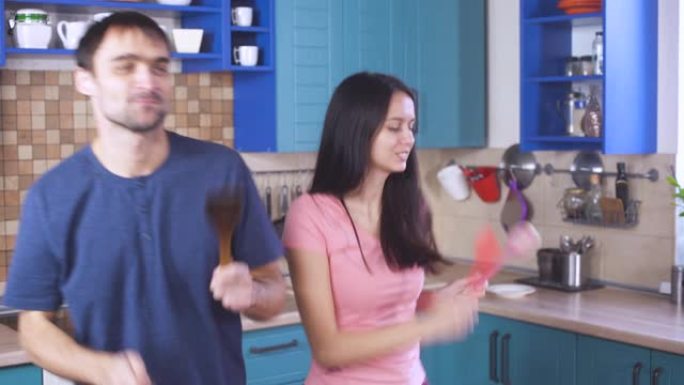 幸福迷人的年轻夫妇在厨房里一起跳舞。快乐的男朋友和女朋友。现代室内的全家福。年轻家庭住宅概念。婚姻关