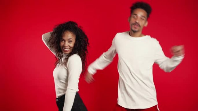 年轻的非洲裔美国夫妇在红色背景工作室孤立地跳舞。派对，快乐，音乐概念。4k。