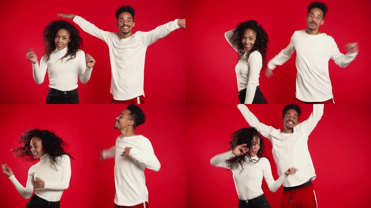 年轻的非洲裔美国夫妇在红色背景工作室孤立地跳舞。派对，快乐，音乐概念。4k。