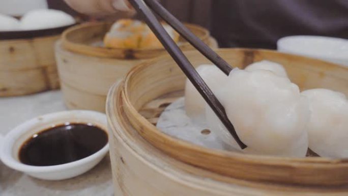 在香港餐厅用筷子从蒸汽煮锅和酱汁混合得到热虾点心