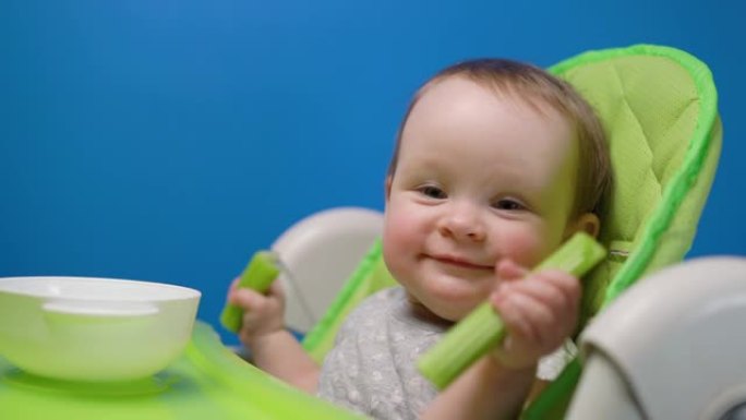 可爱的女婴吃绿色新鲜芹菜棒，看着相机