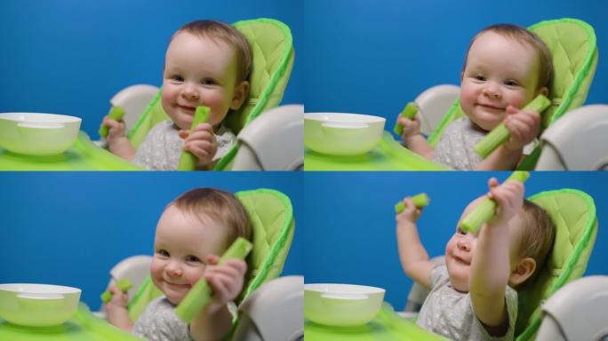 可爱的女婴吃绿色新鲜芹菜棒，看着相机