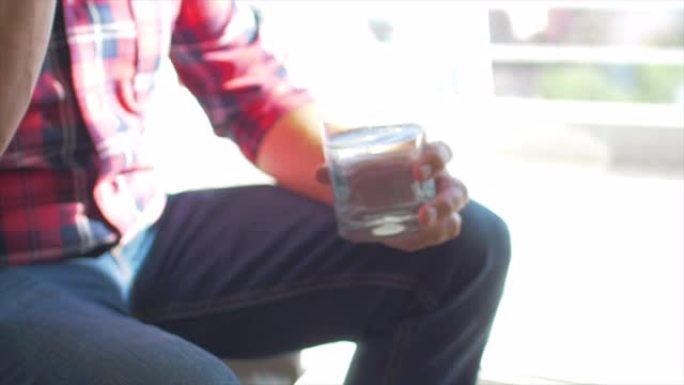 男子服用蓝色药丸药，并从透明玻璃杯中喝水