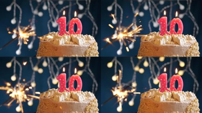 生日蛋糕，蓝色背景上有10个数字粉色蜡烛和烟火。慢动作和特写视图