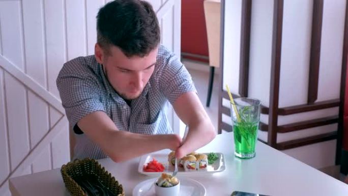 一个截了两只残手的残疾人在咖啡馆用叉子吃寿司卷。