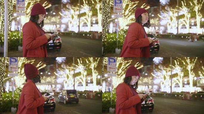 穿着红色连衣裙的年轻亚洲女子晚上在等出租车。