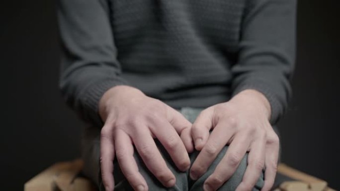 男性双手紧贴膝盖，表现出疼痛抑郁和焦虑。Bulling图标