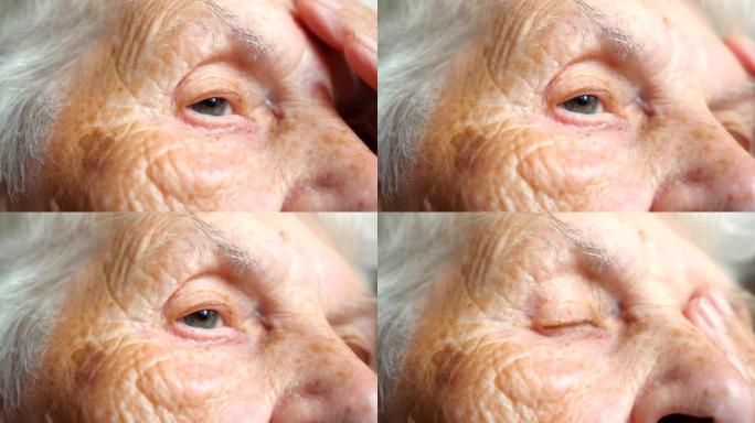 老年妇女看着沉思的肖像。女性脸上有皱纹的特写。祖母平静地望着远方，表现出悲伤或孤独的情绪。细节视图慢