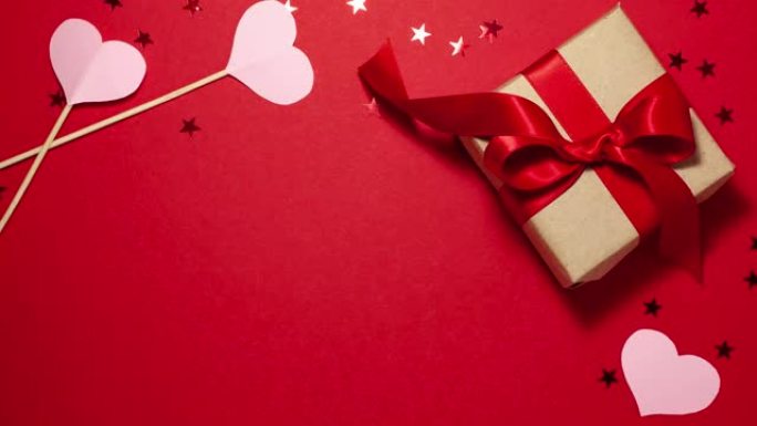 牛皮纸礼品盒，缎面红丝带蝴蝶结和粉色心形平放，红色有复印空间。情人节概念与复制空间