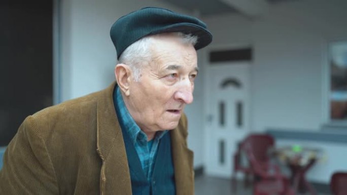 老人养老金领取者的肖像前视图，独自站在户外时穿着夹克和帽子环顾四周