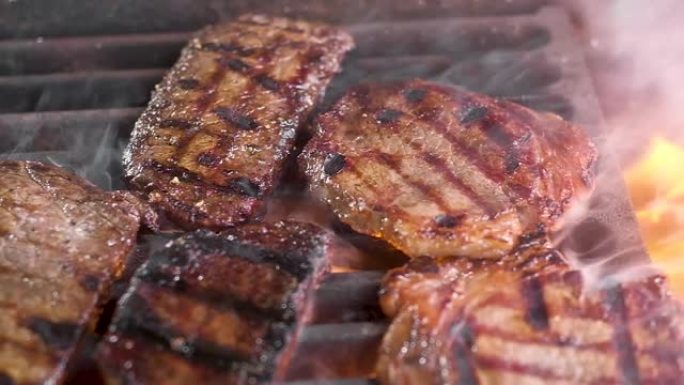 烤架上有多汁的肉排。肉是用火煎的。有烟。摄像机从左向右移动。在大火中烤出美味的牛排。关闭了。