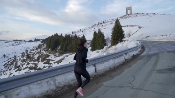 年轻的健身女子在山里慢跑，背景是自由之弧