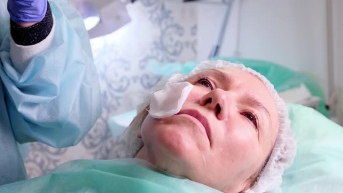 50岁的中年妇女正在由医生美容师向面部注射透明质酸。美容程序。特写