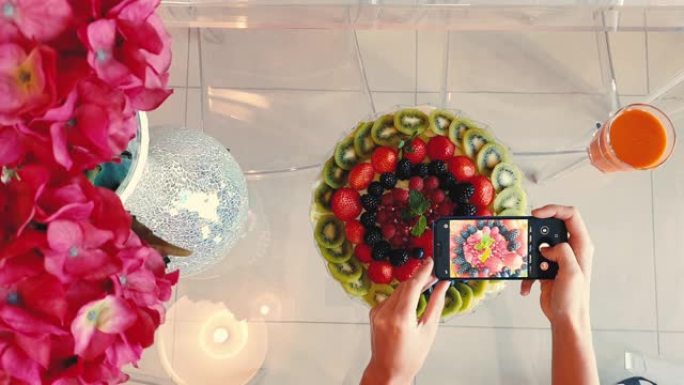 女人在智能手机上拍摄水果盘子的照片