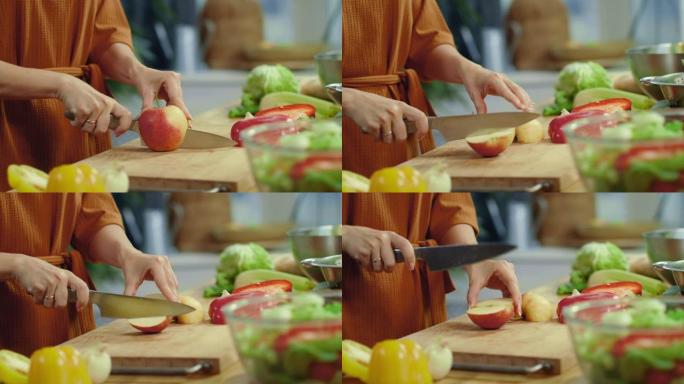 女人的手在厨房里切红苹果。家庭主妇烹饪蔬菜沙拉。