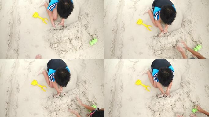 暑假亚洲家庭旅游休闲出海男孩玩沙子与活跃在海滩上，独自在下午建造了一座沙堡
