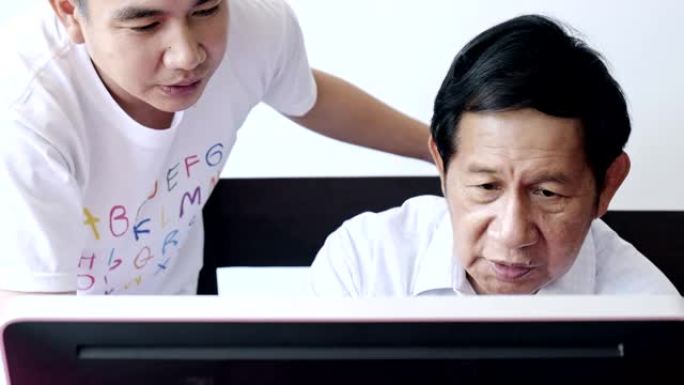 高年级男子学习使用计算机。亚洲老人家里有年轻人。注重学习。
