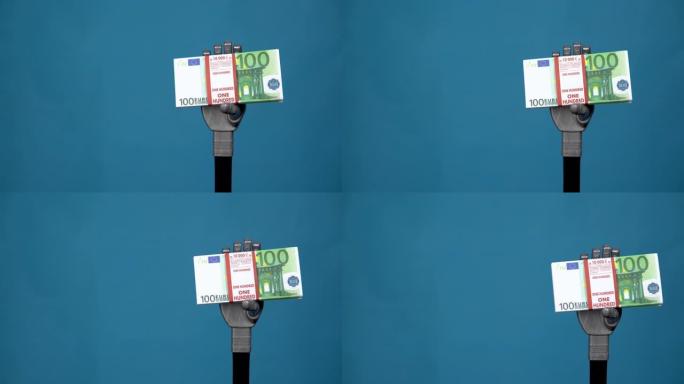 一只机械手拿着一捆欧元。灰色的半机械手在蓝色背景上拿着钱。4k