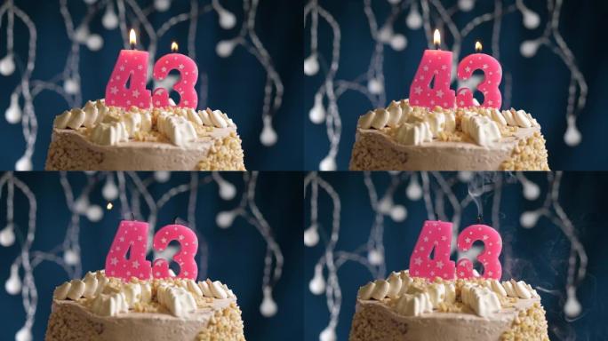 蓝色背景上有43号粉色蜡烛的生日蛋糕。蜡烛吹灭了。慢动作和特写视图
