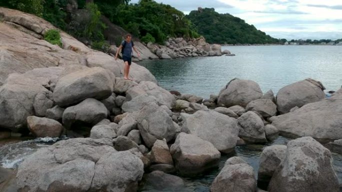 背包旅行者走在海边的岩石上