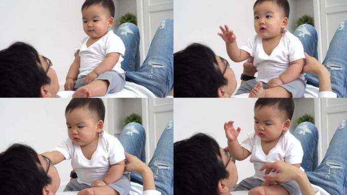 周末在家休息时，可爱的亚洲男婴坐在父母身上，抚摸着父亲的脸