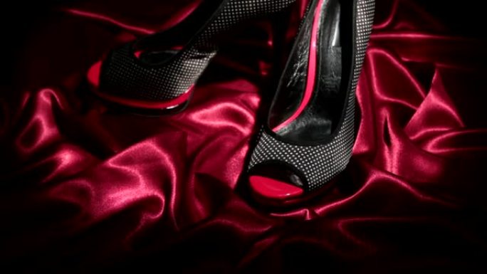 变焦。两只黑色厚底细高跟鞋，红色皱巴巴的织物上有饰钉。