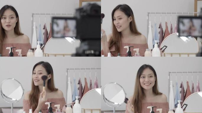 美丽的亚洲女人博主正在展示如何化妆和使用化妆品。在镜头前在家录制vlog视频直播。社交媒体概念上的商