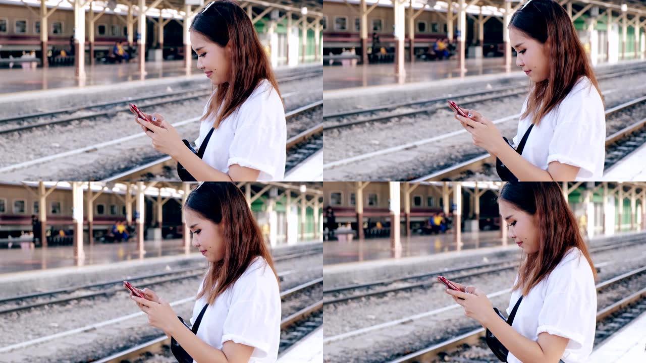 在曼谷的backgorund，用手机在火车站等待火车的中拍。亚洲女人。