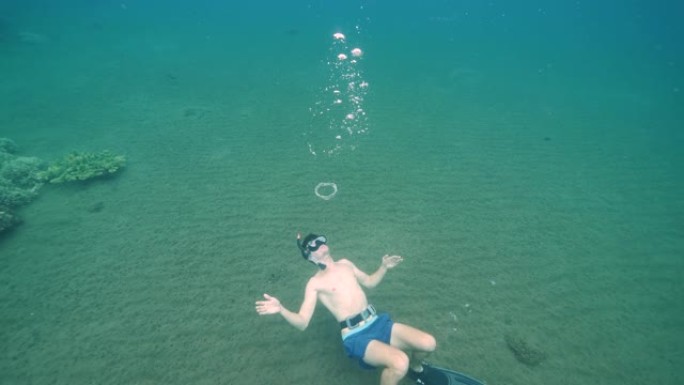男性自由潜水者在水下吹泡泡环。
