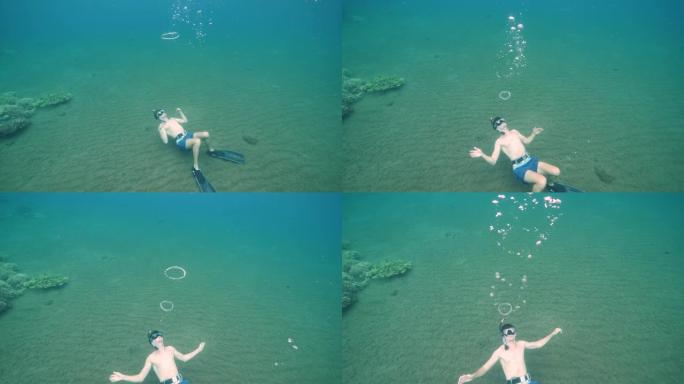 男性自由潜水者在水下吹泡泡环。