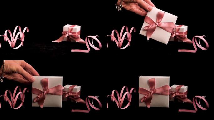 女性手放置礼物盒，粉色和黑色背景上有粉色丝带