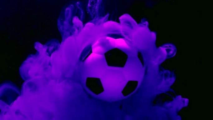 足球在惊人的空间背景。深蓝色背景上的紫色和粉红色墨水