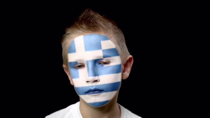 希腊足球队的悲伤球迷。一个脸上涂着民族色彩的孩子。