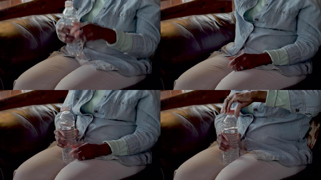 老年黑人妇女从她腿上拿着的水瓶中喝水