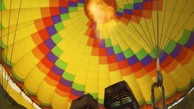 带有热火焰的燃烧器的特写镜头照亮了飞行的热气球内部