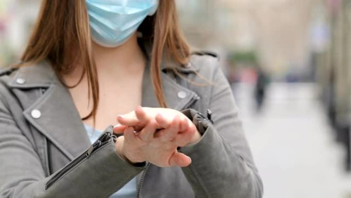 戴防护面具的女人用消毒剂清洁手