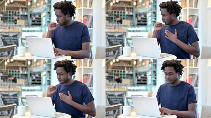 咳嗽的非洲男子在咖啡馆里用笔记本电脑工作