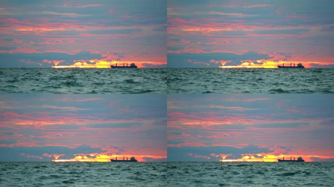 货船停泊在海上和日落天空的暗红色云